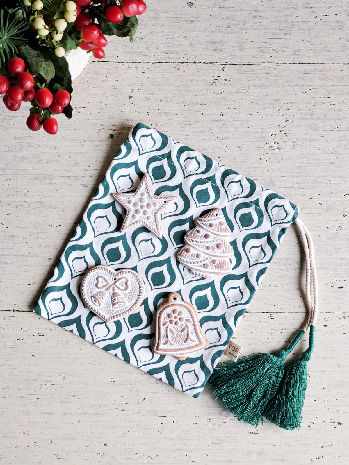 Handmade terracotta sugar saver ornament with a natural jute rope, displayed in a green drawstring pouch, perfect for holiday gifting.