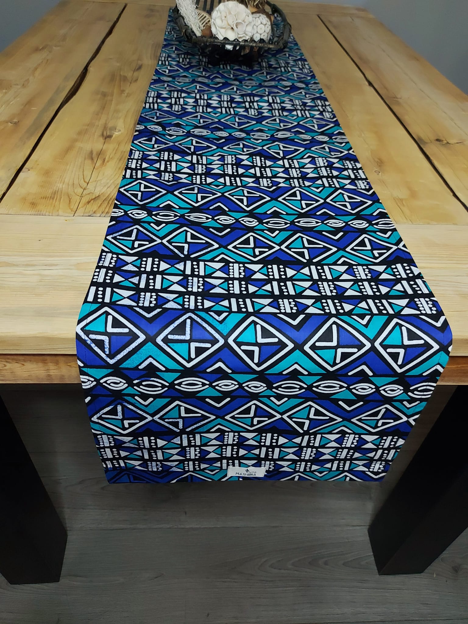 Handmade table runner featuring vibrant African prints, available in three sizes, elegantly draped on a dining table.