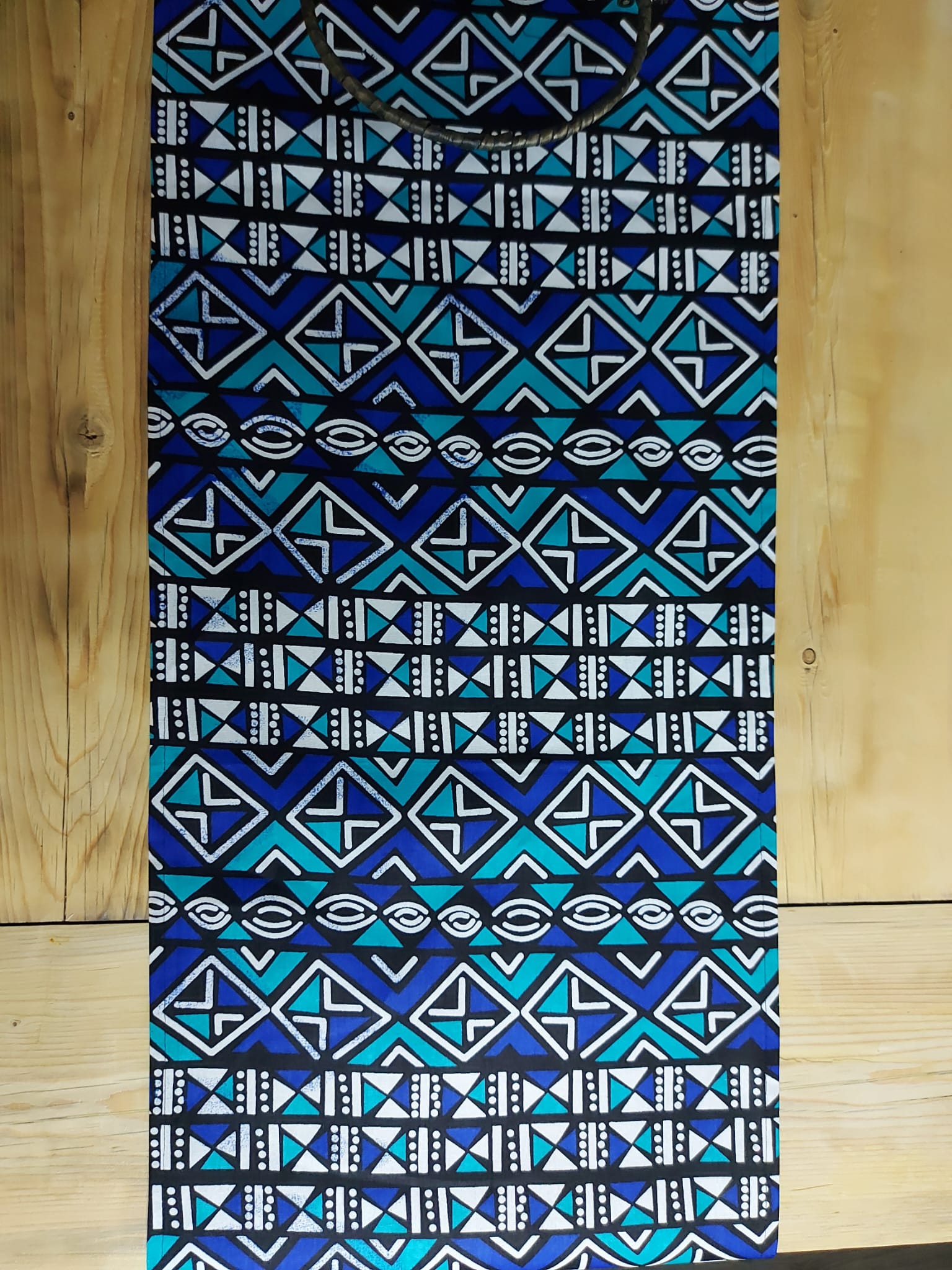 Handmade table runner featuring vibrant African prints, available in three sizes, elegantly draped on a dining table.