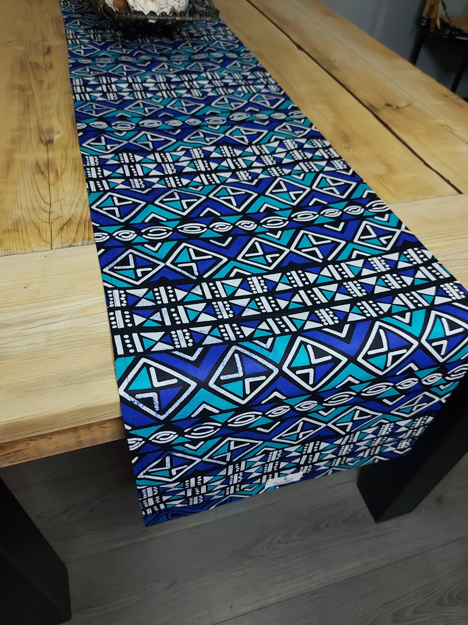 Handmade table runner featuring vibrant African prints, available in three sizes, elegantly draped on a dining table.