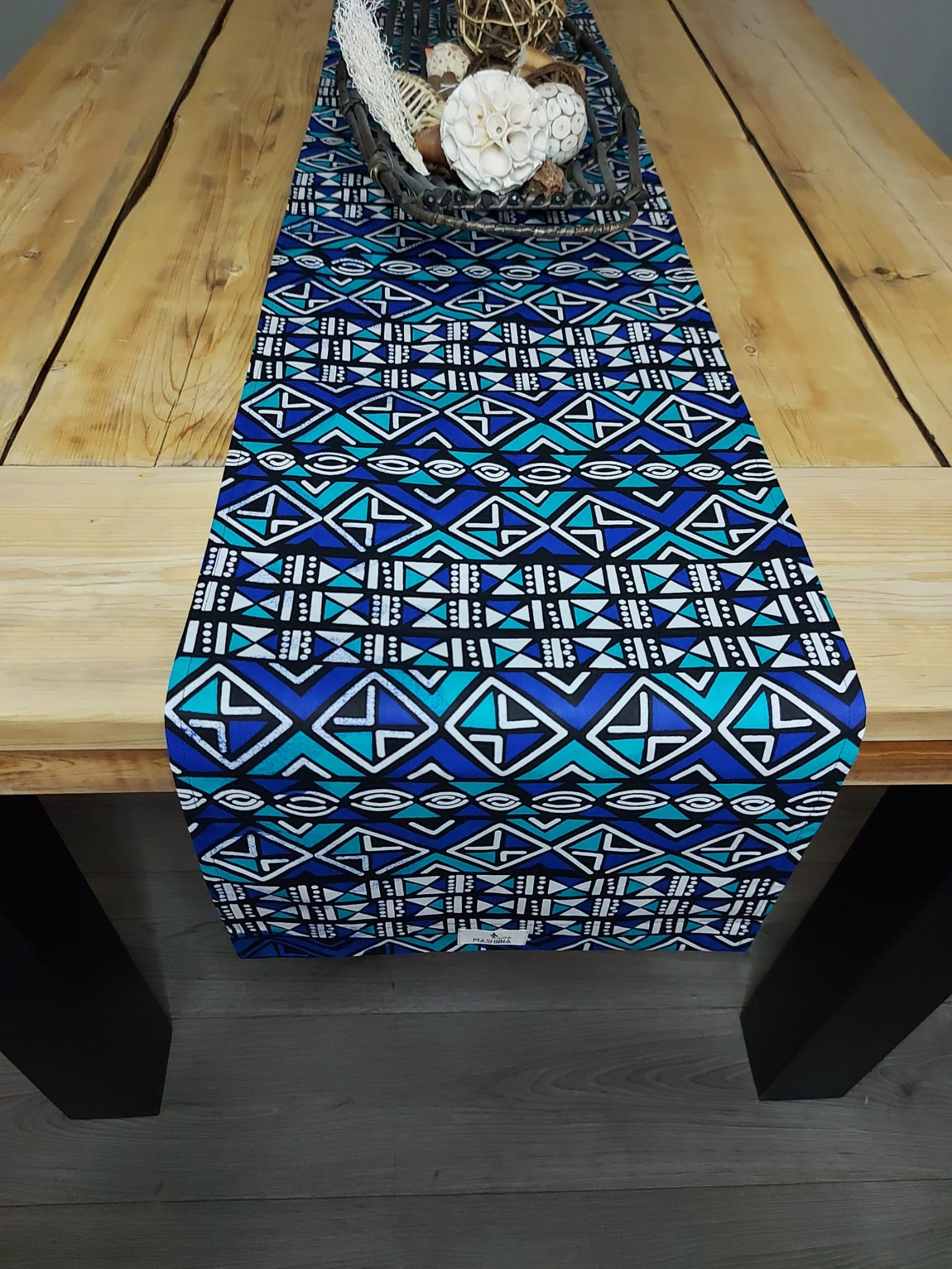 Handmade table runner featuring vibrant African prints, available in three sizes, elegantly draped on a dining table.