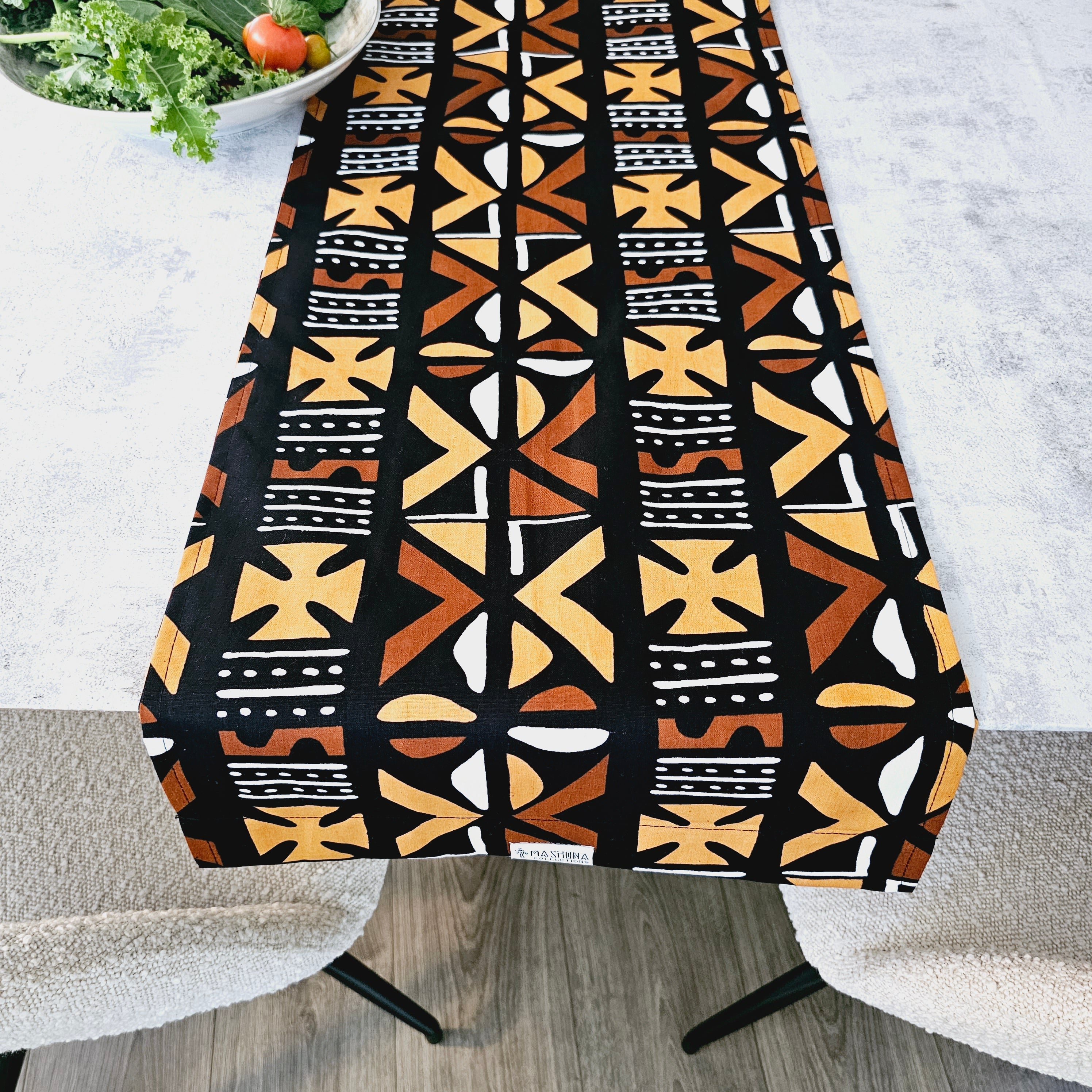 Handmade table runner featuring vibrant African prints, available in three sizes, elegantly draped over a dining table.