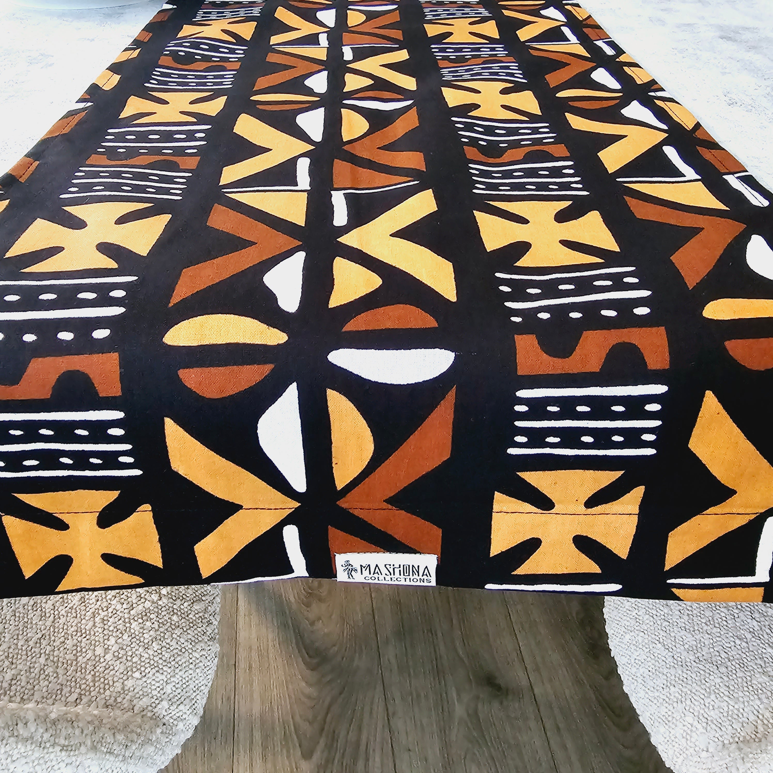 Handmade table runner featuring vibrant African prints, available in three sizes, elegantly draped over a dining table.