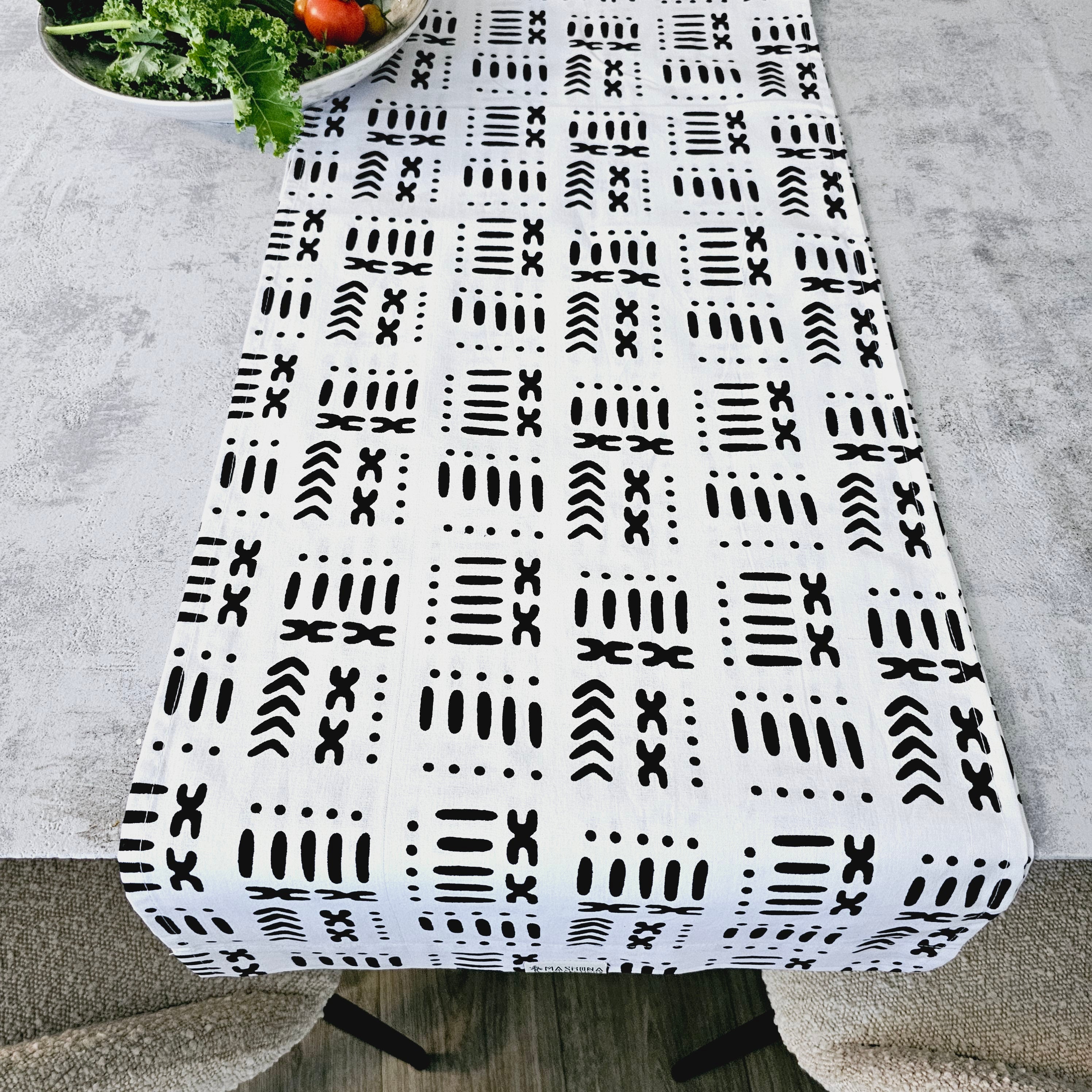 A vibrant handmade table runner featuring unique African prints, available in multiple sizes, elegantly draped over a dining table.