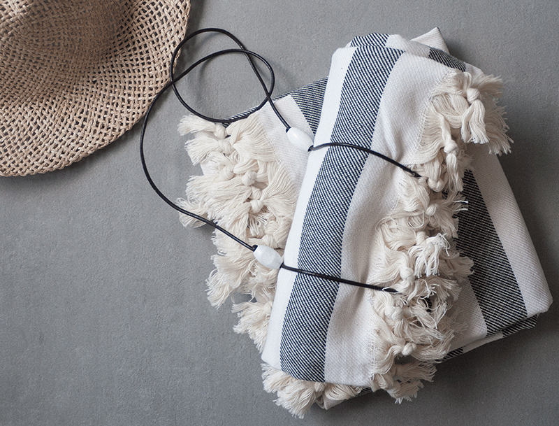 A stylish handmade towel strap made of leather with wood pearls, perfect for securing towels and picnic blankets.