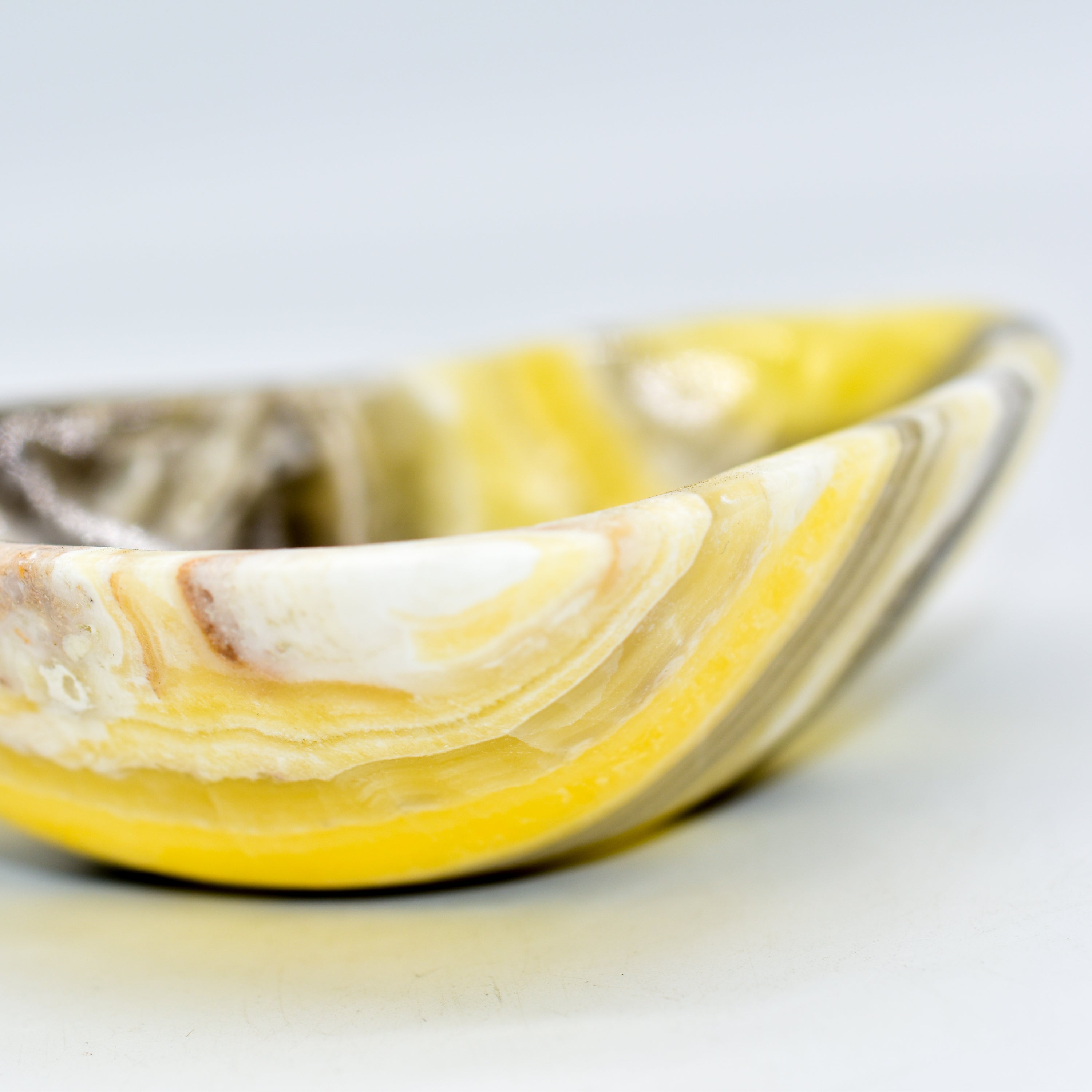 A beautifully handcrafted heart-shaped onyx bowl in zebra, amber, and white colors, showcasing its unique craftsmanship.