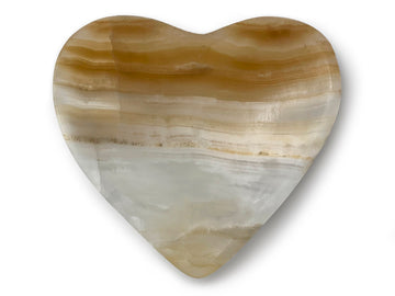 A beautifully handcrafted heart-shaped onyx bowl in zebra, amber, and white colors, showcasing its unique craftsmanship.