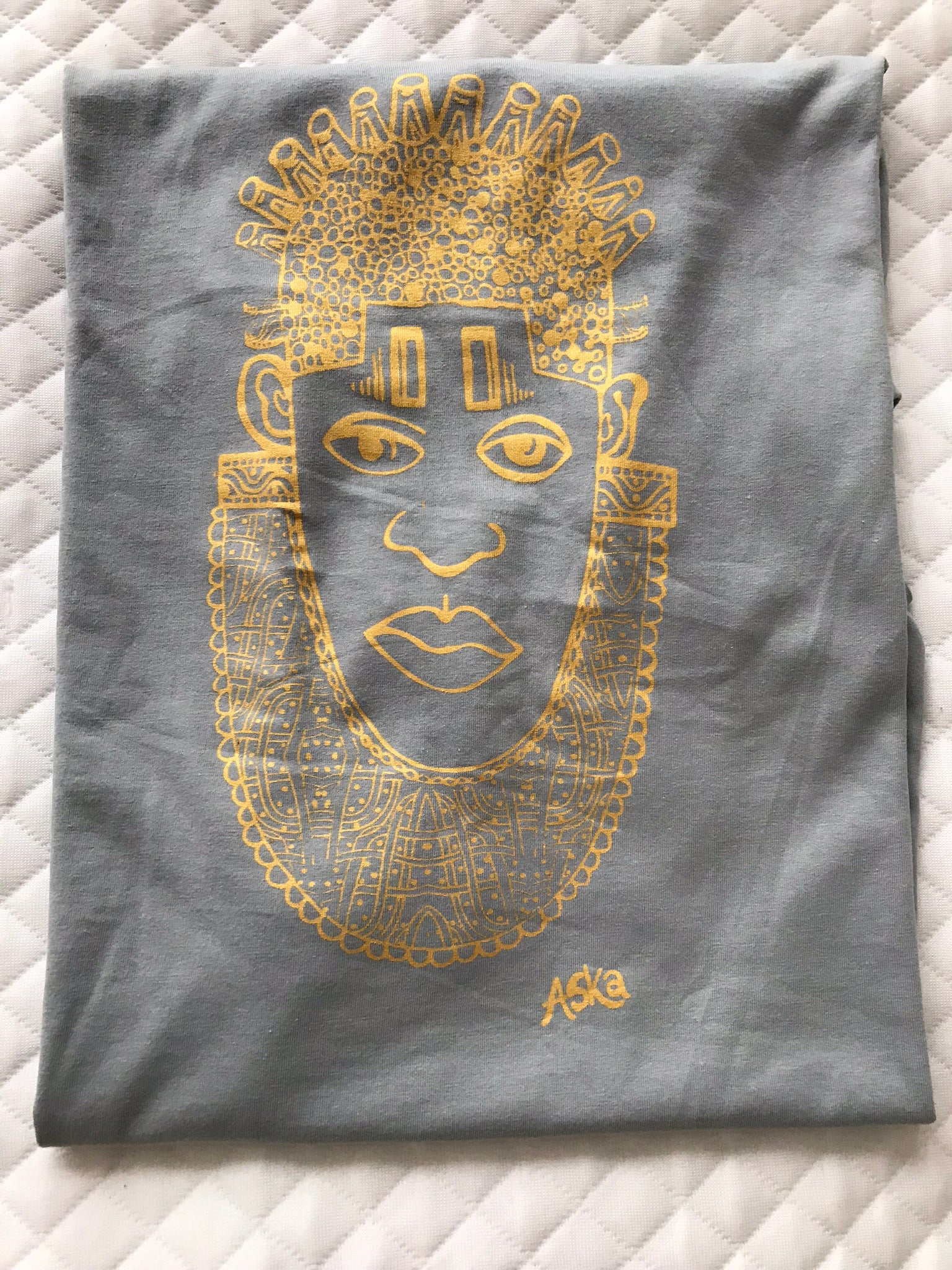 IDIA Art Earth Positive Tee in Gold on Grey featuring a contemporary design of Queen IDIA from the Benin Kingdom, made from 100% organic cotton.