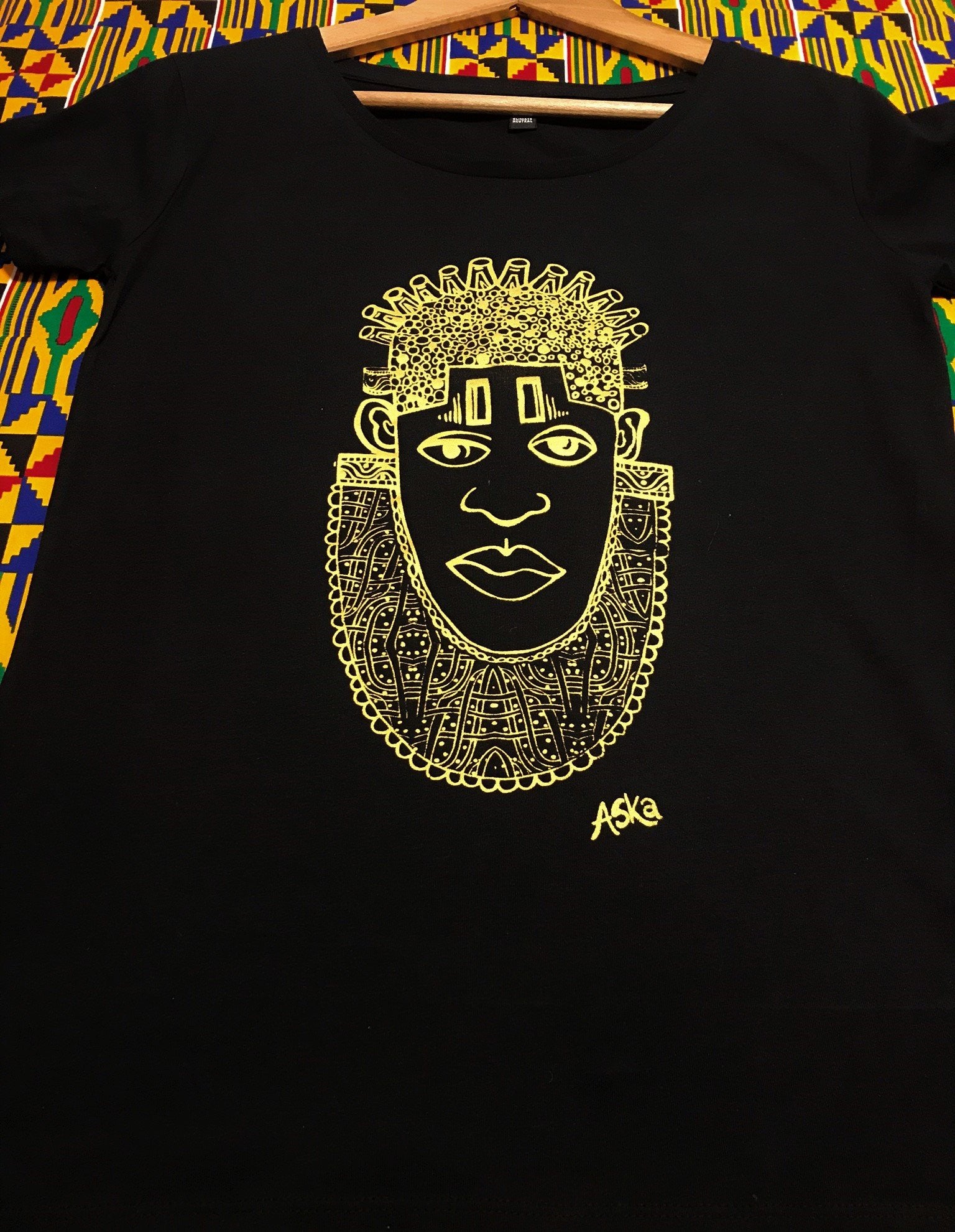 IDIA in Gold Art Earth Positive Tee featuring a gold print of Queen Idia on a black scooped neck shirt made from 100% organic cotton.