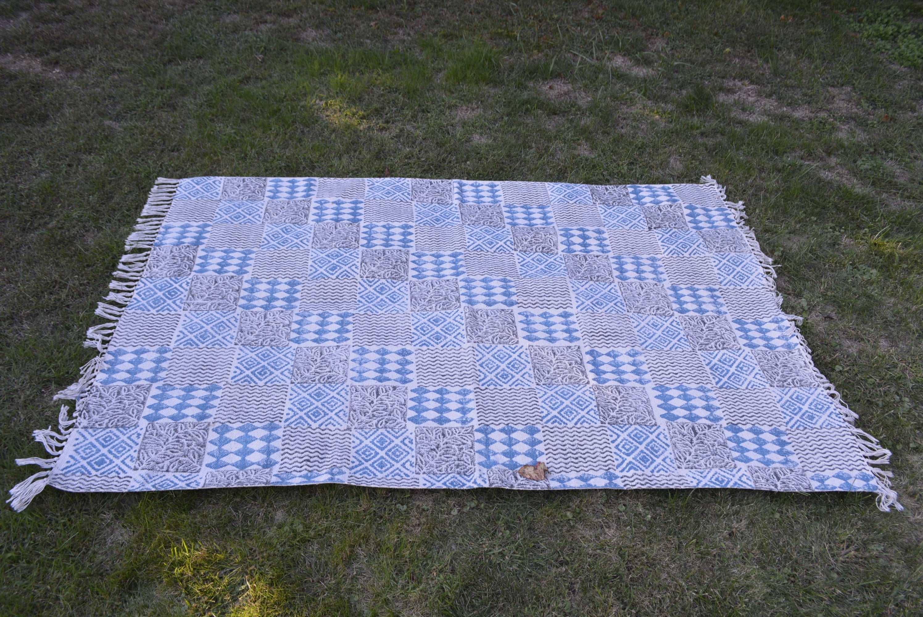 Indigo dyed handwoven cotton rug featuring a floral design, showcasing intricate block printing and a beautiful blue background.