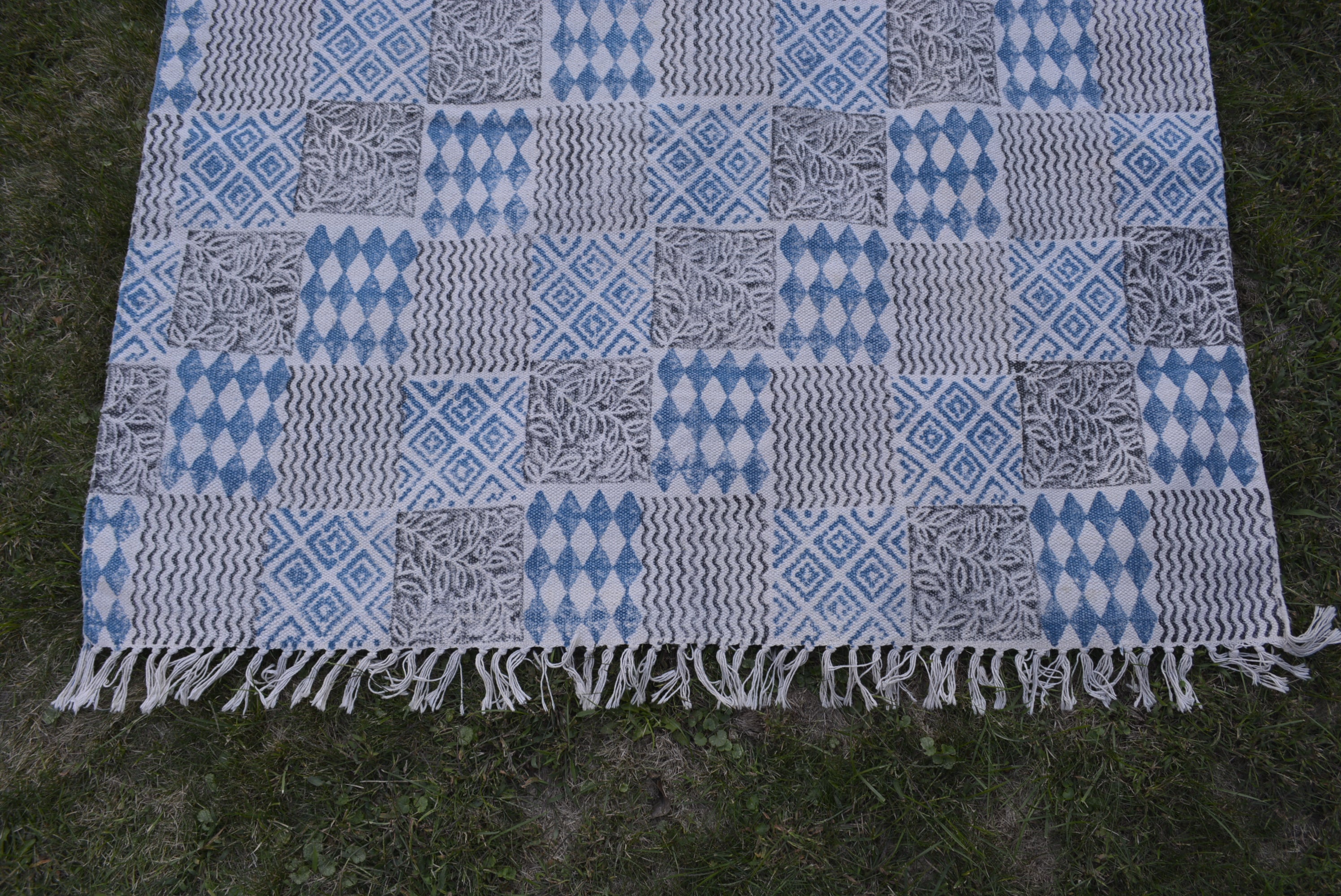 Indigo dyed handwoven cotton rug featuring a floral design, showcasing intricate block printing and a beautiful blue background.