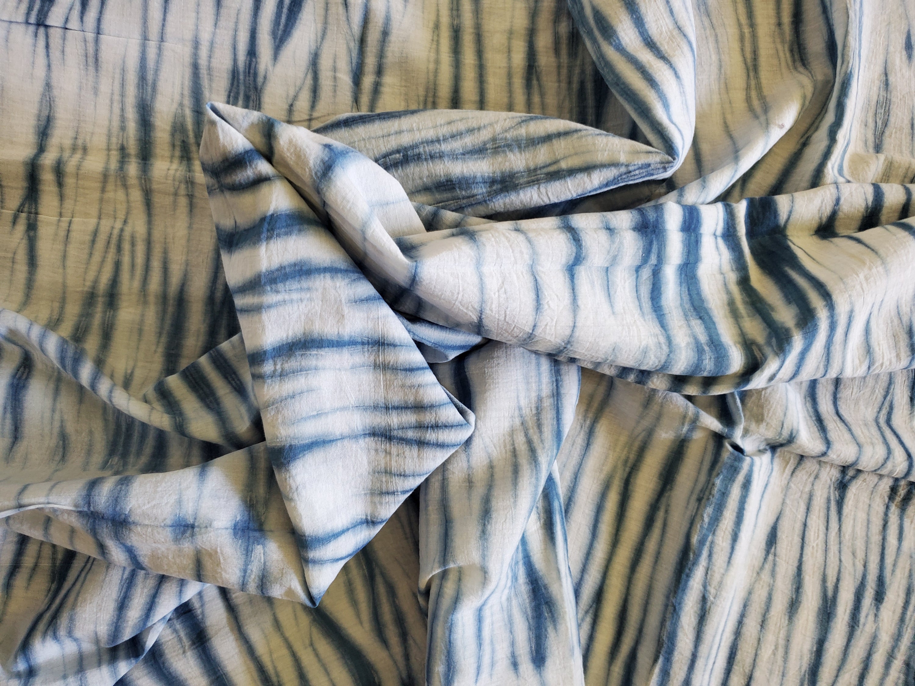 Indigo Ridge Cotton Fabric featuring a hand-dyed ridge pattern in indigo blue on white background, showcasing unique artisan craftsmanship.