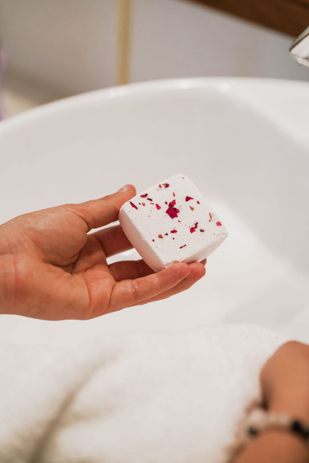 A collection of colorful Individual Shower Fizzies in various scents, displayed in a serene bathroom setting.