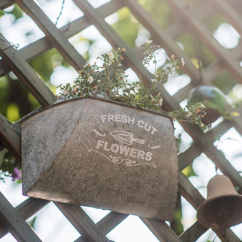 Iron Flower Wall Planter in gray with white letters, showcasing a stylish design for indoor and outdoor use.