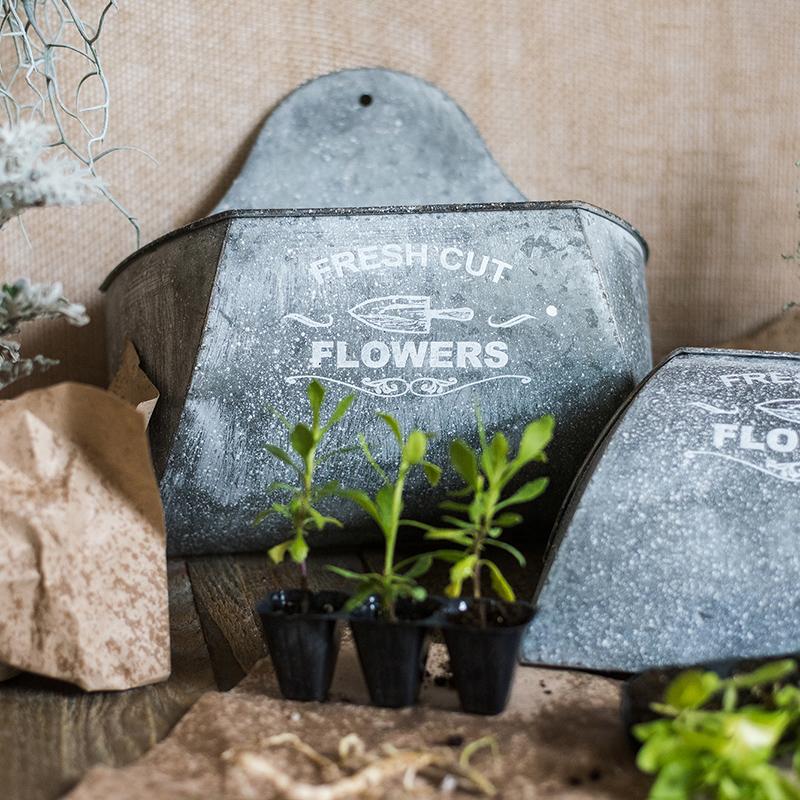 Iron Flower Wall Planter in gray with white letters, showcasing a stylish design for indoor and outdoor use.