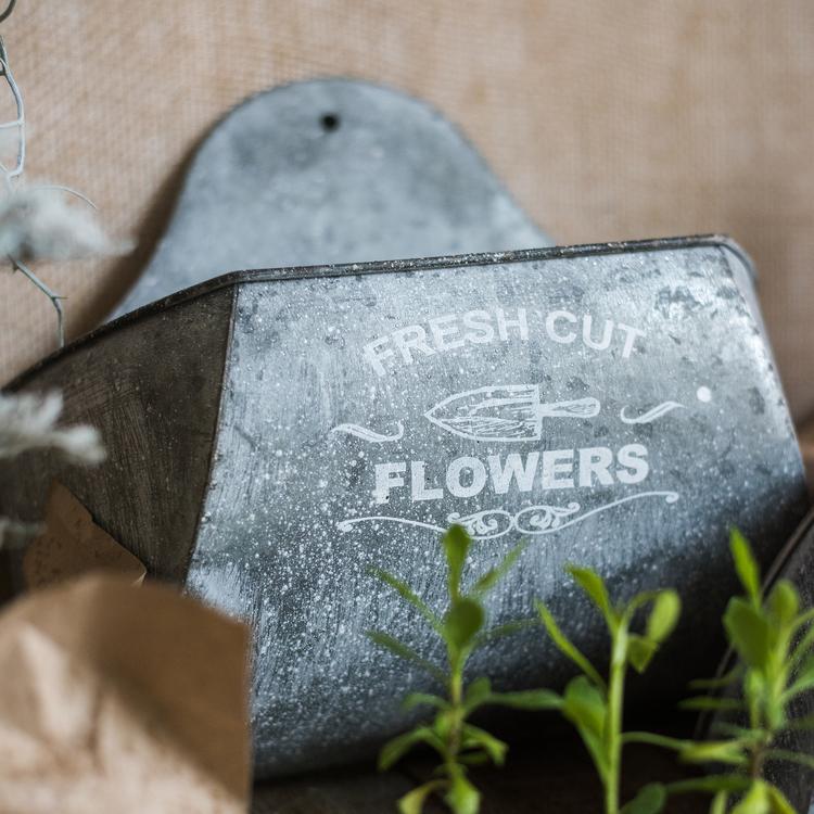 Iron Flower Wall Planter in gray with white letters, showcasing a stylish design for indoor and outdoor use.