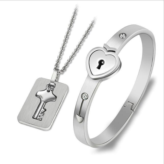 Stainless steel jewelry set featuring a lover lock bangle bracelet and key pendant necklace in silver, gold, and rosa gold colors.