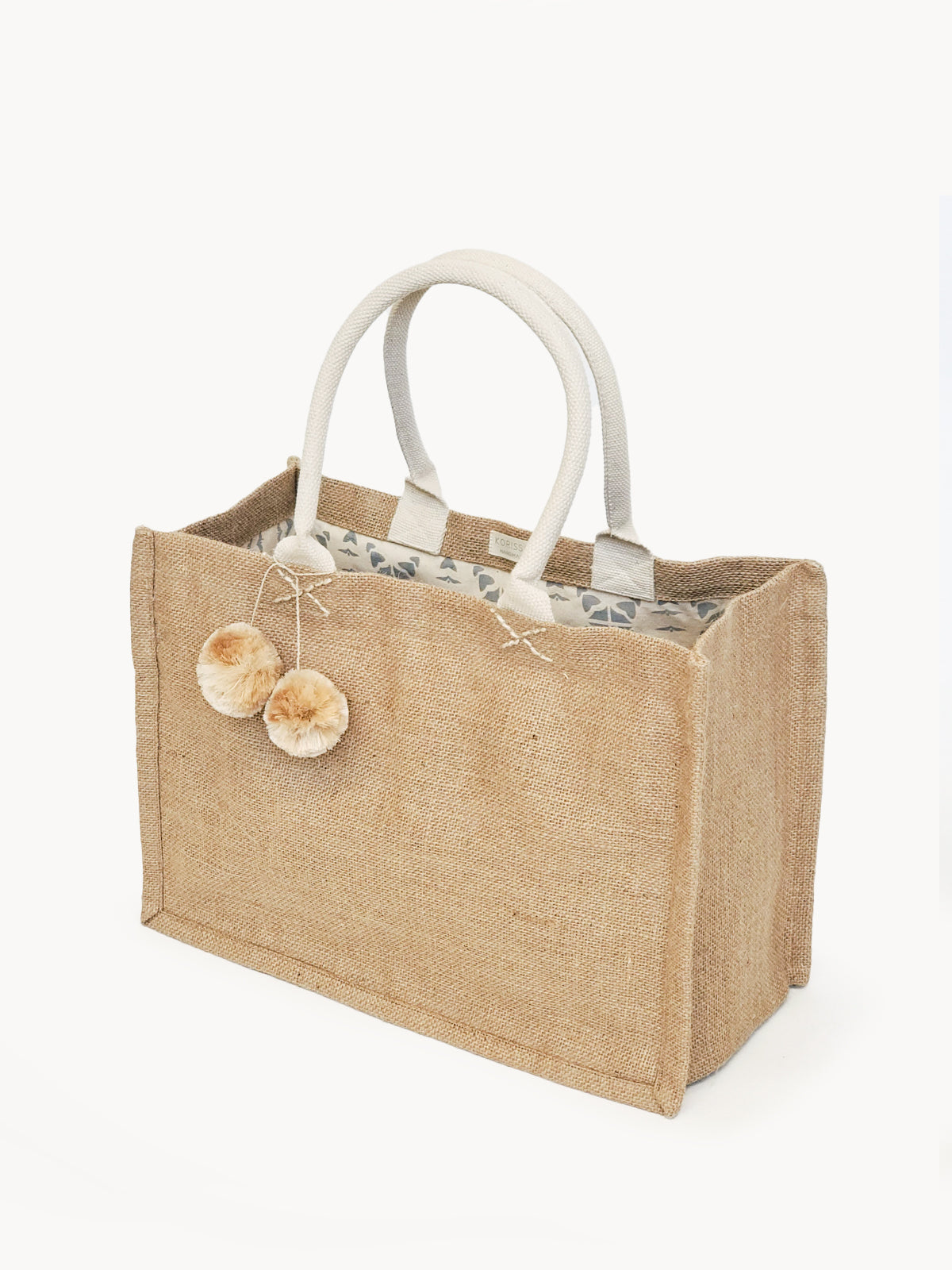 Eco-friendly jute canvas shopping bag with colorful pompom, showcasing its natural texture and spacious design.