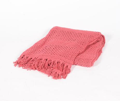 A hand-knitted coral red throw with tassels, showcasing intricate craftsmanship and vibrant color.