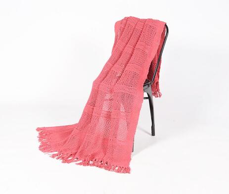 A hand-knitted coral red throw with tassels, showcasing intricate craftsmanship and vibrant color.