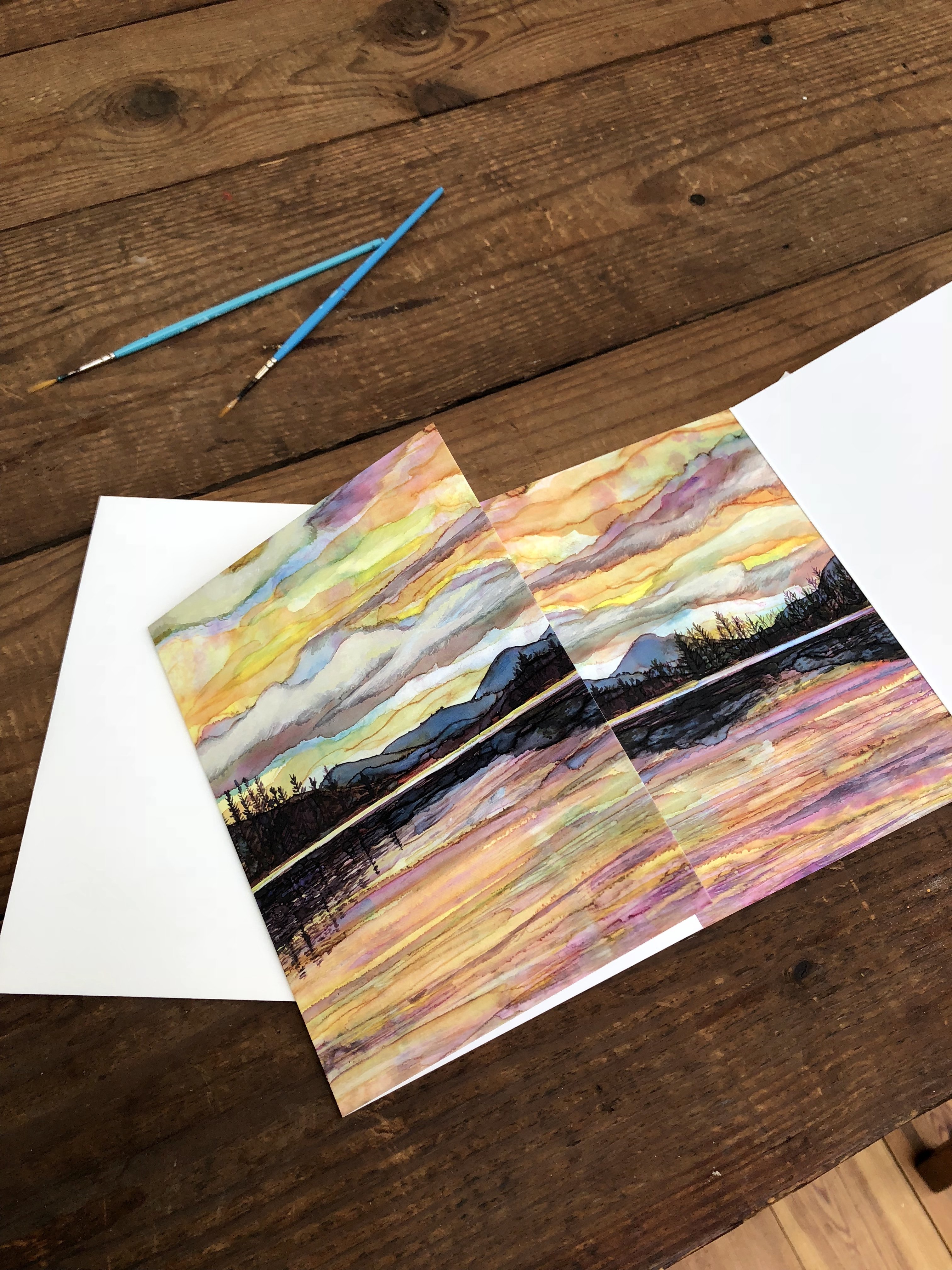 Lake Sunset Greeting Card featuring dual landscape paintings on the cover and inside, printed on heavyweight matte paper.