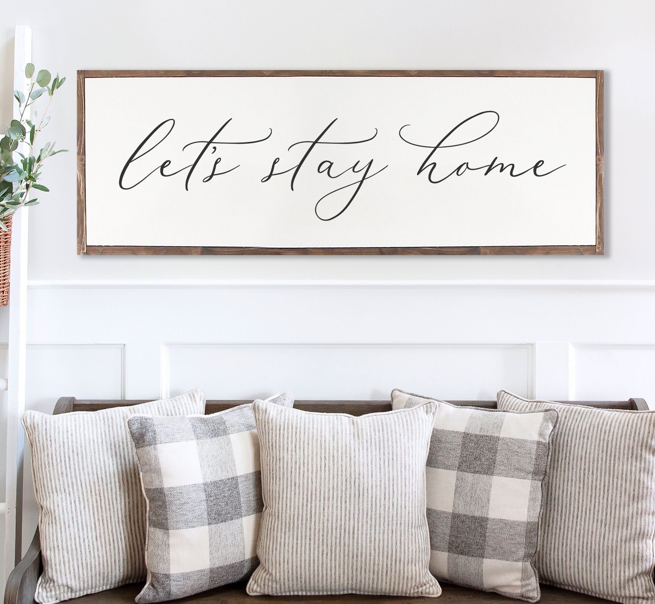 Rustic 'Let's Stay Home' farmhouse wood sign with unique wood grain and painted lettering, framed in customizable stain color.