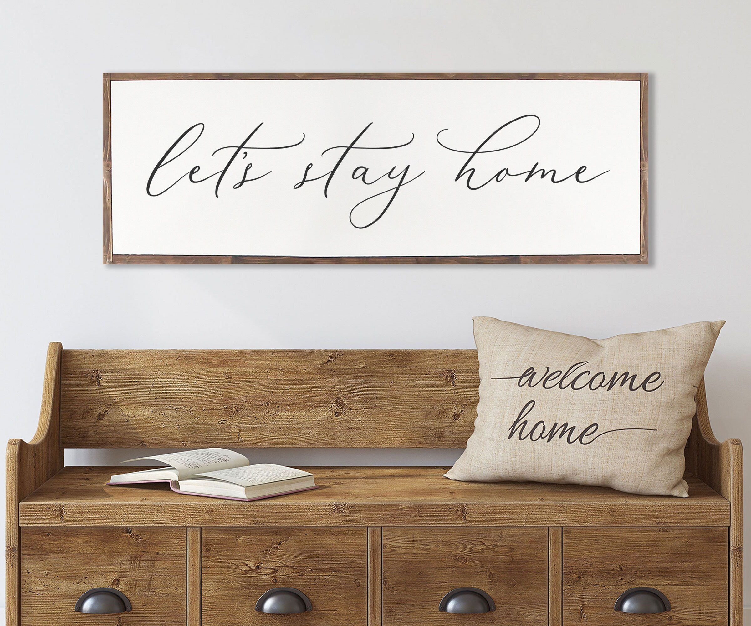 Rustic 'Let's Stay Home' farmhouse wood sign with unique wood grain and painted lettering, framed in customizable stain color.