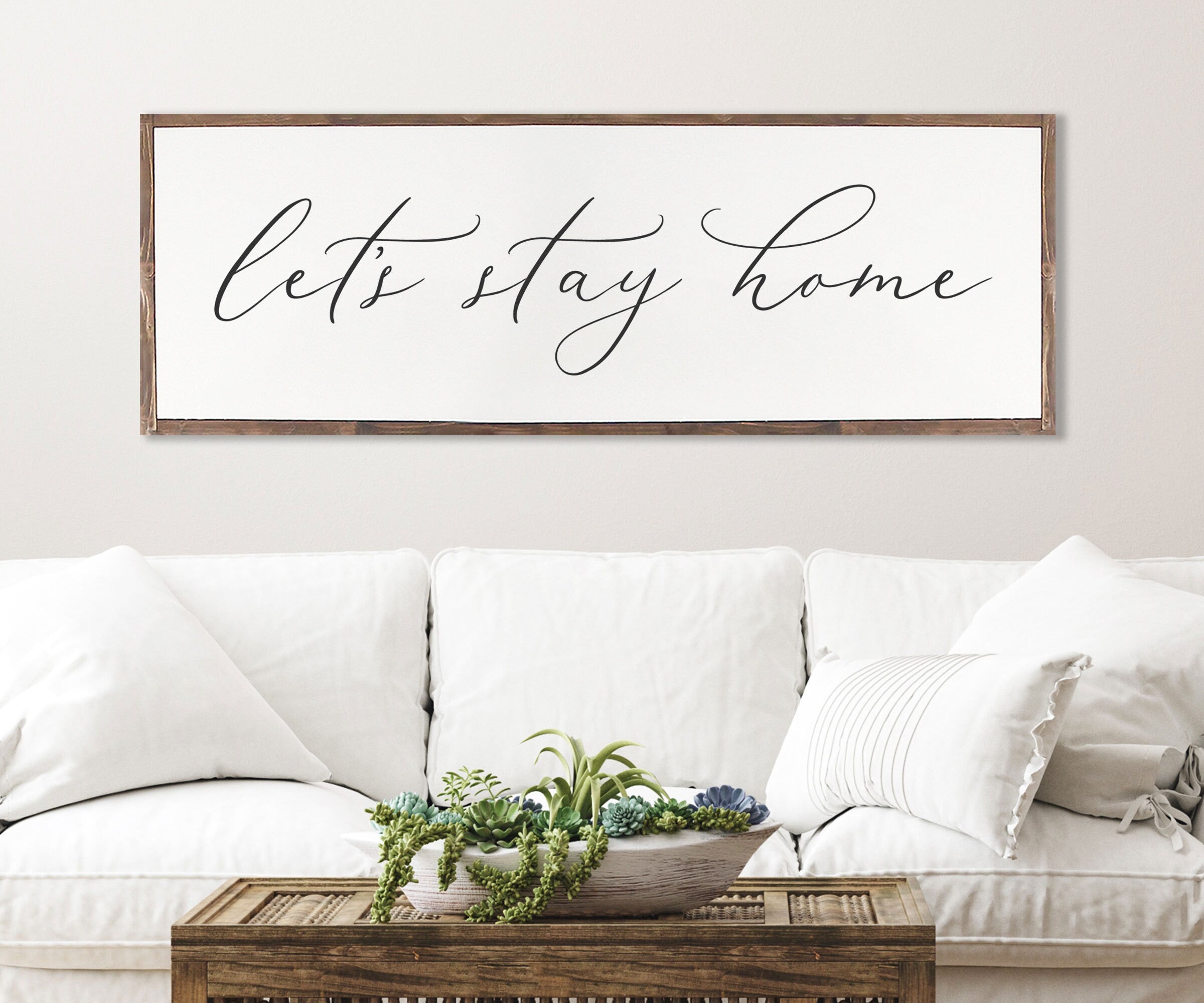 Rustic 'Let's Stay Home' farmhouse wood sign with unique wood grain and painted lettering, framed in customizable stain color.