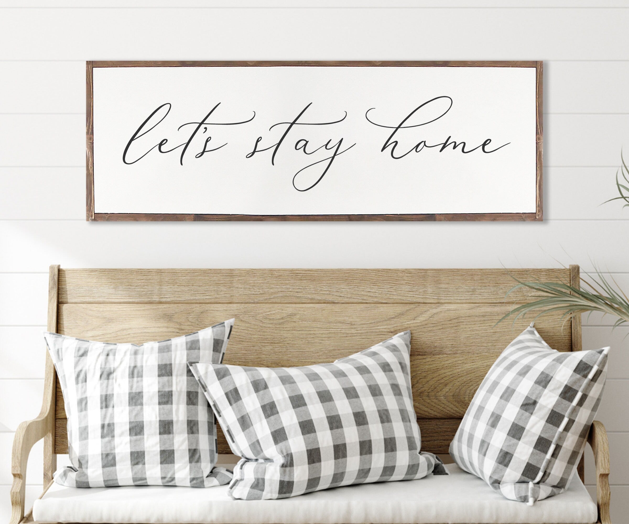 Rustic 'Let's Stay Home' farmhouse wood sign with unique wood grain and painted lettering, framed in customizable stain color.