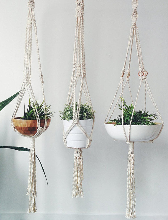 A stylish macrame plant hanger made from natural cotton rope, showcasing a beautiful plant suspended in the air with intricate knot designs.