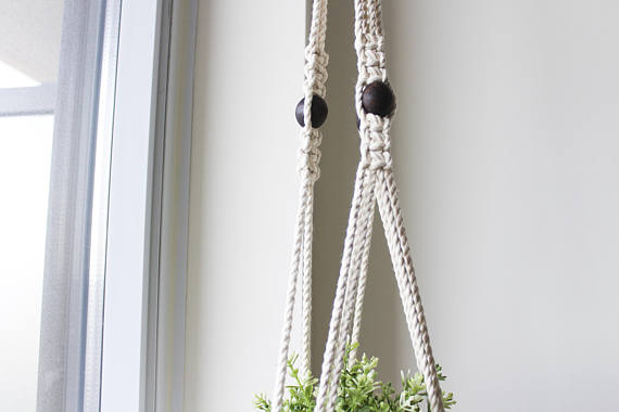 A beautifully crafted macrame plant hanger made from 100% cotton rope with textured wooden beads, showcasing a stylish design suitable for indoor and outdoor use.