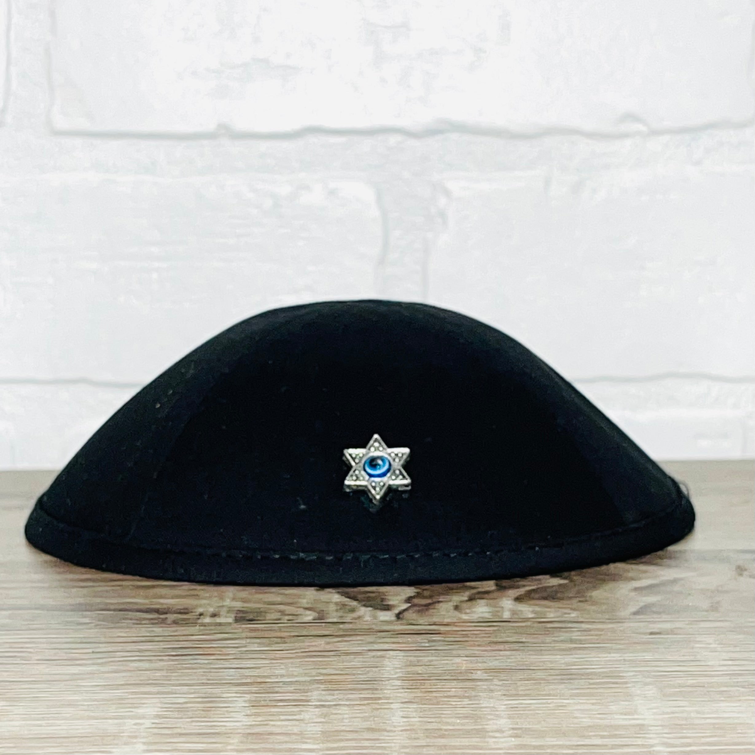 A beautifully crafted Magen David Kippah featuring a blue Evil Eye, available in black cotton, denim, and white linen.