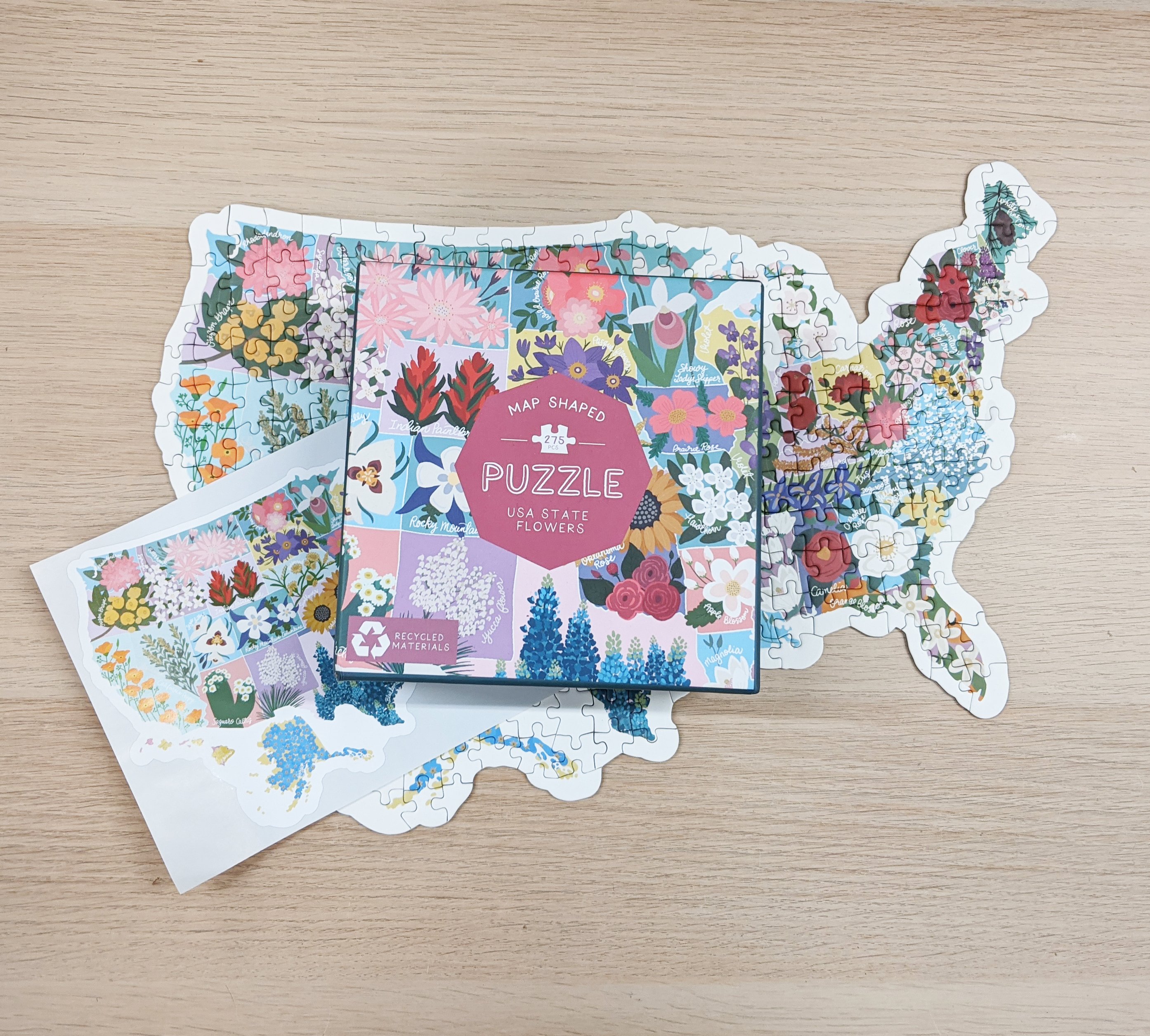 Map shaped jigsaw puzzle featuring US state flowers, colorful and detailed design with unique pieces.