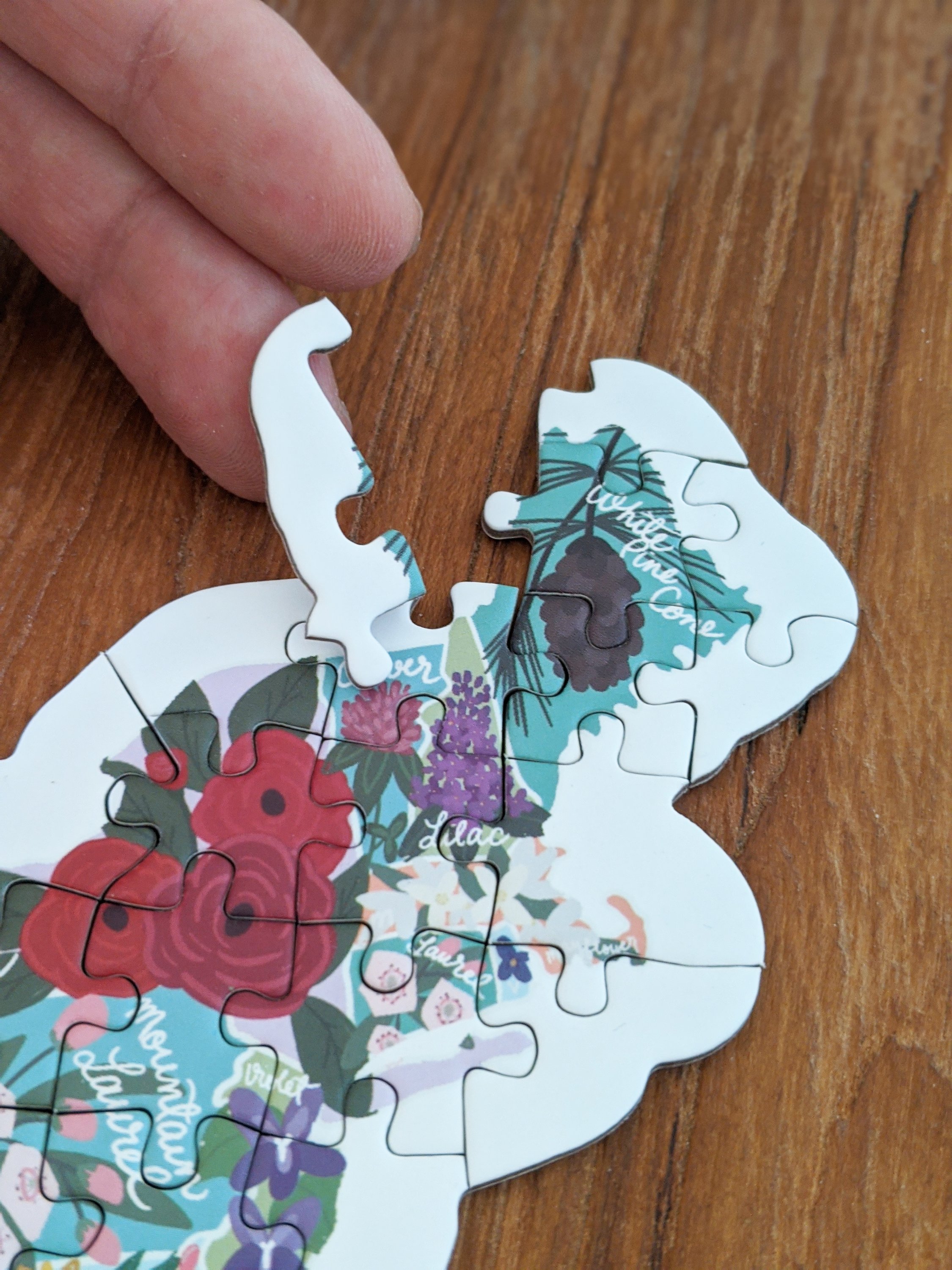 Map shaped jigsaw puzzle featuring US state flowers, colorful and detailed design with unique pieces.