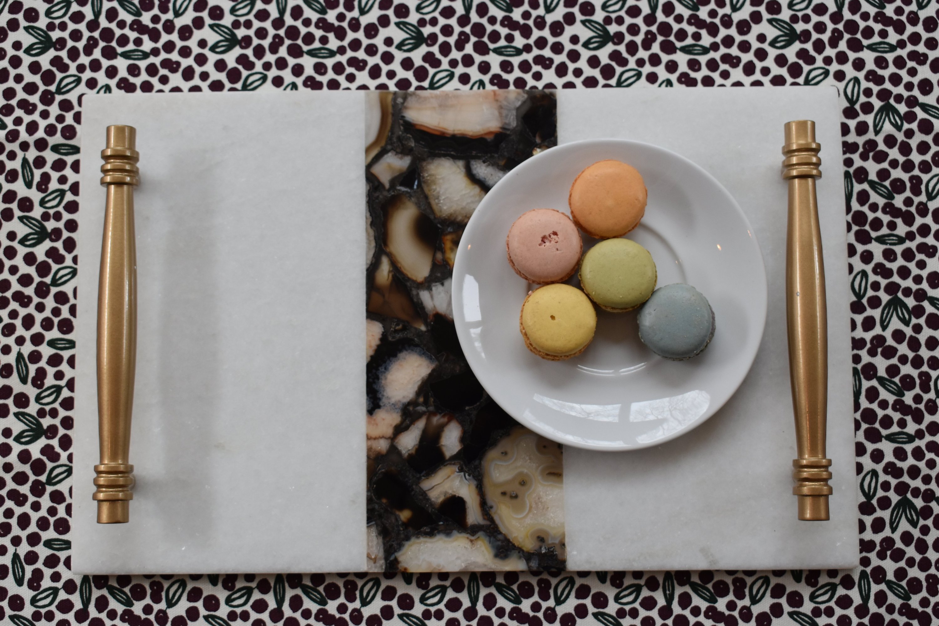 A stylish marble serving tray with gold handles and an intricate agate inlay design, perfect for serving snacks and sweets.