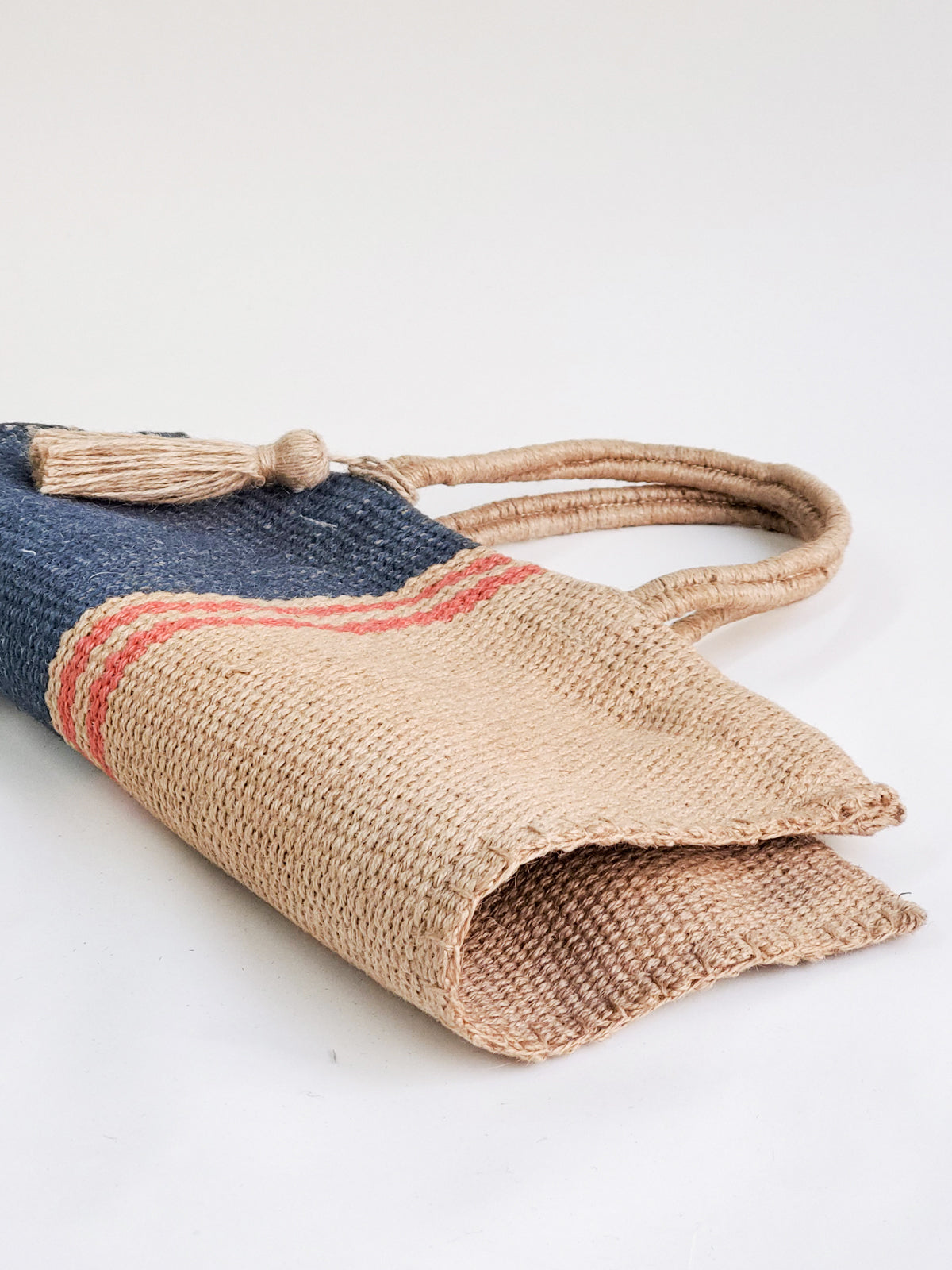 Maya Jute Tote Bag in natural, navy, and red colors, showcasing its handwoven texture and spacious design.