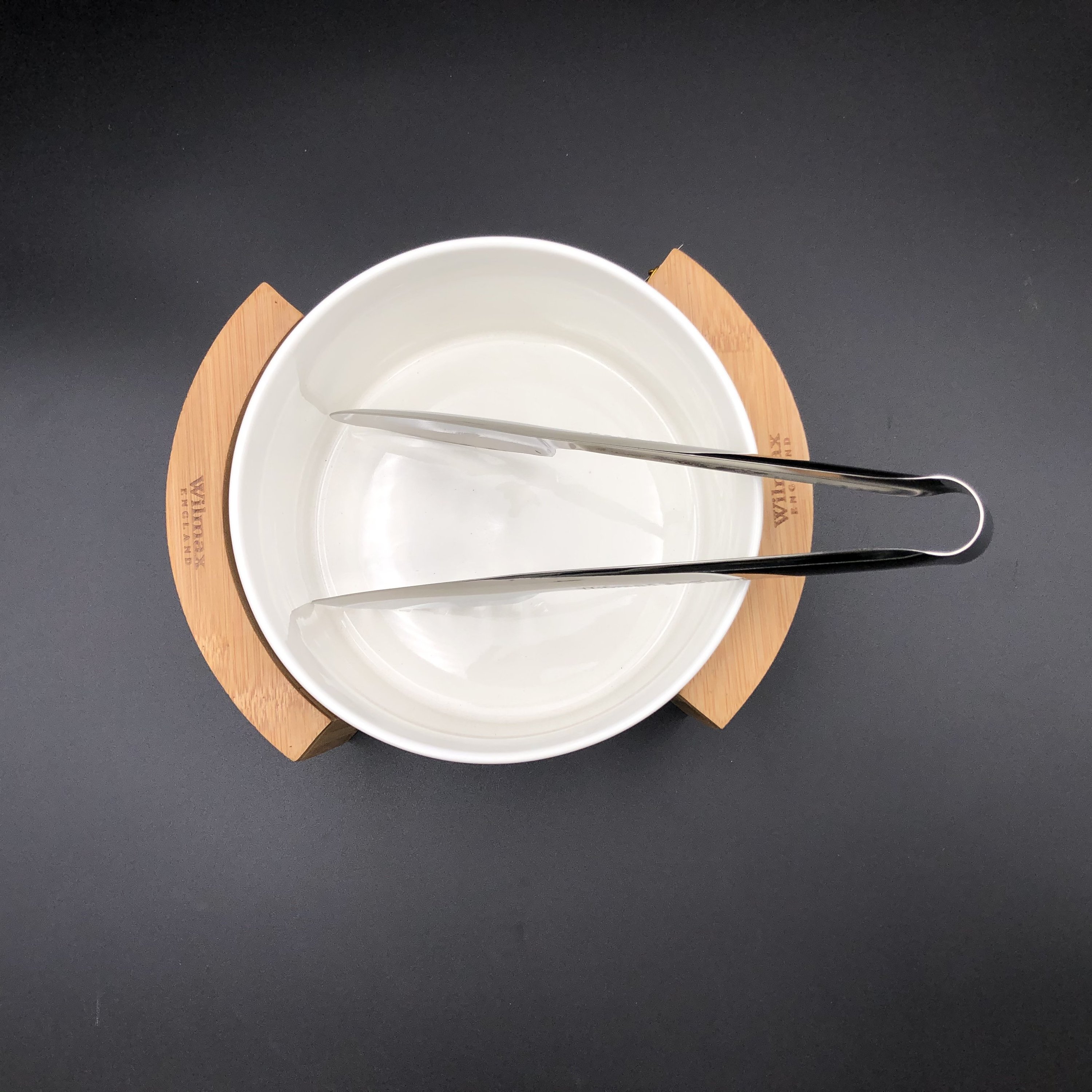 Medium salad bowl set featuring a fine porcelain bowl, stainless steel serving tongs, and a bamboo stand for elegant dining.