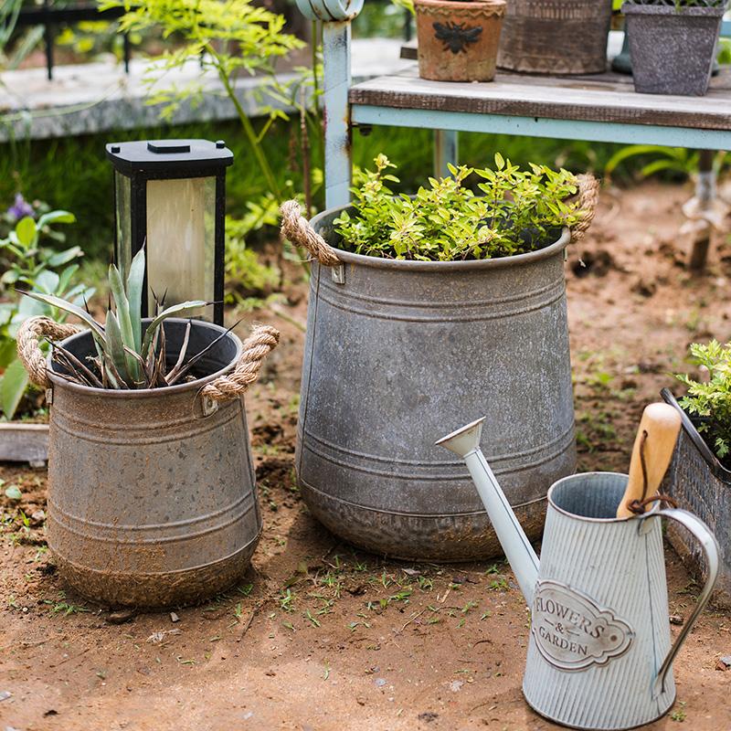 Metal flower pail with rope handles in gray and rusty colors, perfect for decorative floral arrangements.