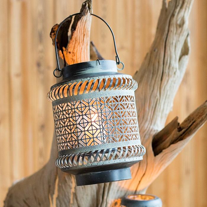 A rustic metal lantern candle holder made of rusted iron, showcasing unique colors and shapes, perfect for home decor.