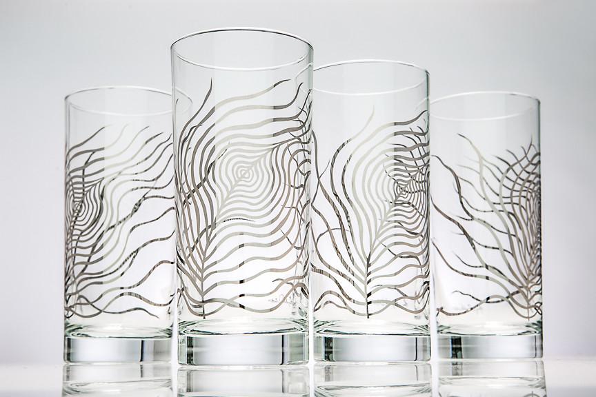 A pair of elegant metallic silver glasses featuring a peacock feather design, reflecting light beautifully.