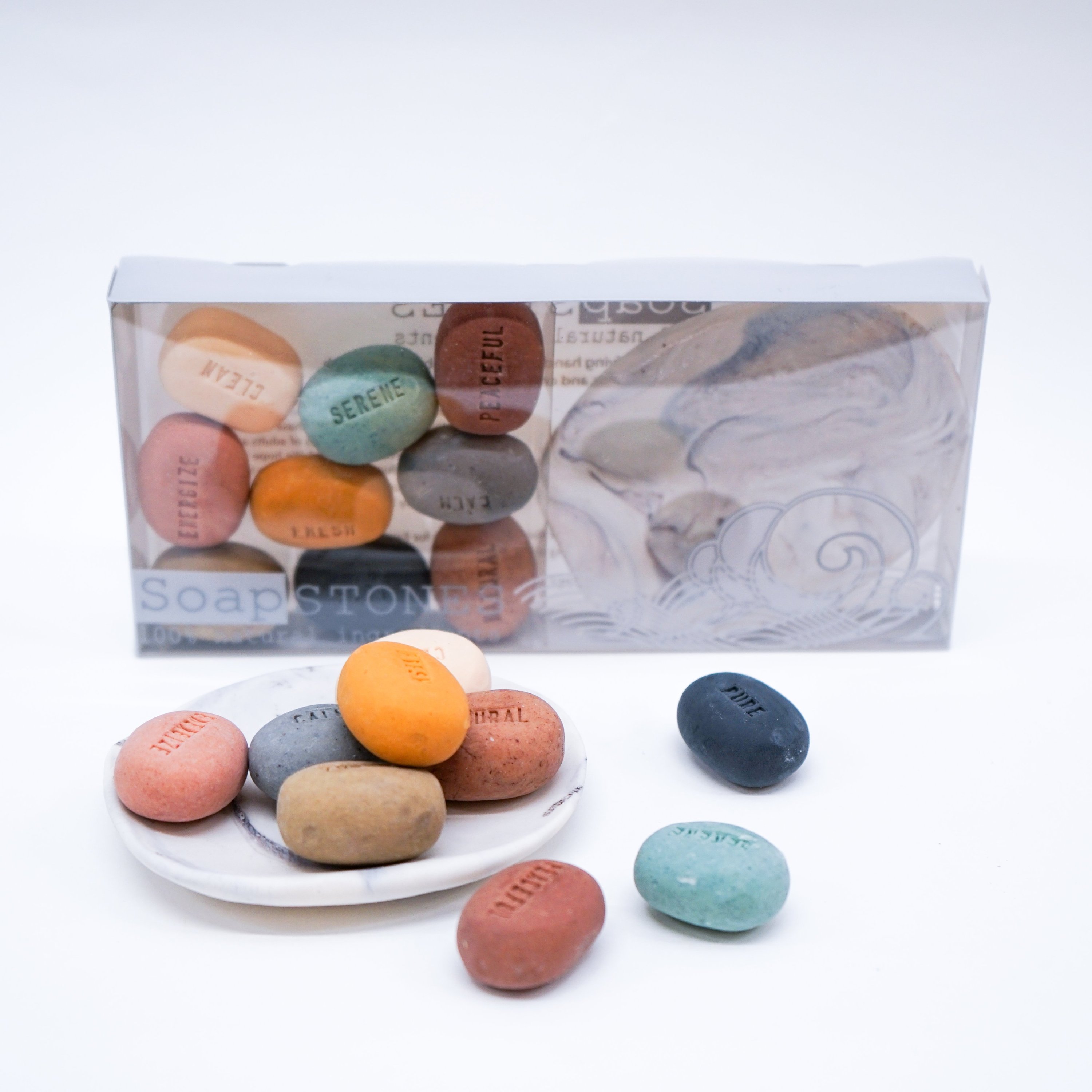 A collection of handmade Mood Soaps in pebble design with a white porcelain dish featuring a dark grey marble effect.