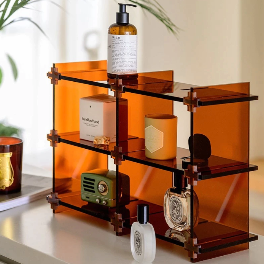 A modern acrylic counter shelf displaying books and decorative items, showcasing its stylish and compact design.