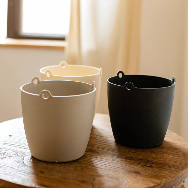 Modern resin hanging planter in black, light gray, and white, featuring a nylon rope and metal hook, designed for artificial plants.