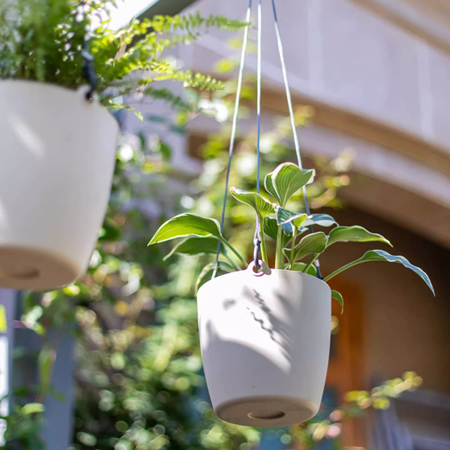 Modern resin hanging planter in black, light gray, and white, featuring a nylon rope and metal hook, designed for artificial plants.