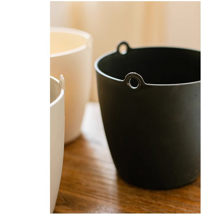 Modern resin hanging planter in black, light gray, and white, featuring a nylon rope and metal hook, designed for artificial plants.