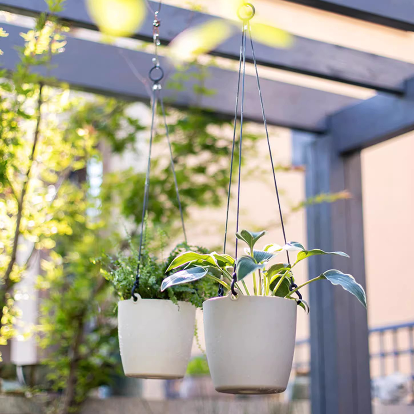 Modern resin hanging planter in black, light gray, and white, featuring a nylon rope and metal hook, designed for artificial plants.