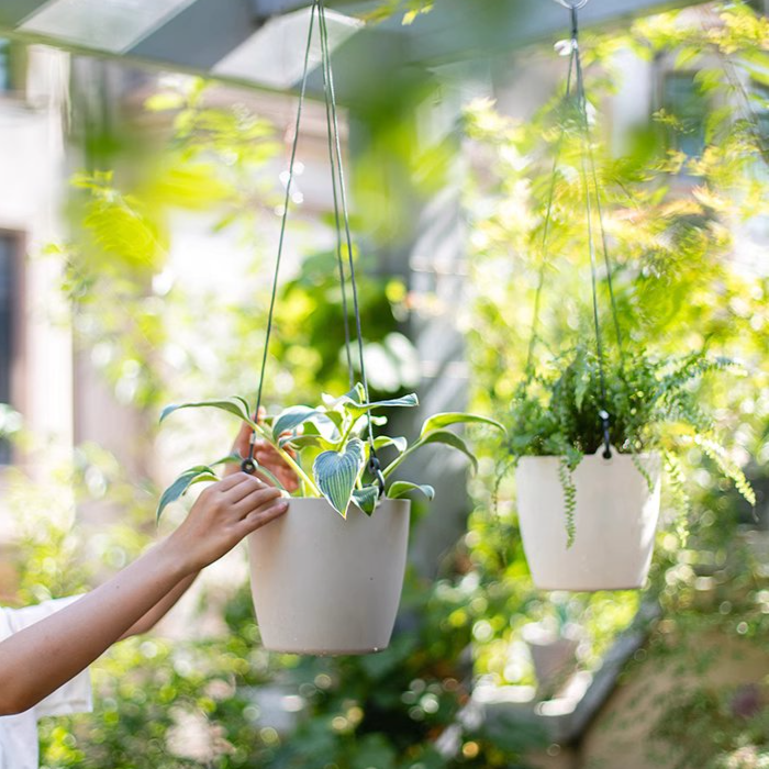 Modern resin hanging planter in black, light gray, and white, featuring a nylon rope and metal hook, designed for artificial plants.