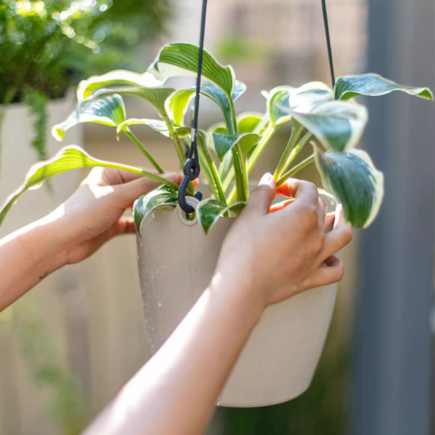 Modern resin hanging planter in black, light gray, and white, featuring a nylon rope and metal hook, designed for artificial plants.