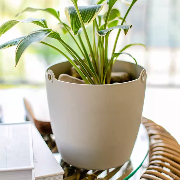 Modern resin hanging planter in black, light gray, and white, featuring a nylon rope and metal hook, designed for artificial plants.