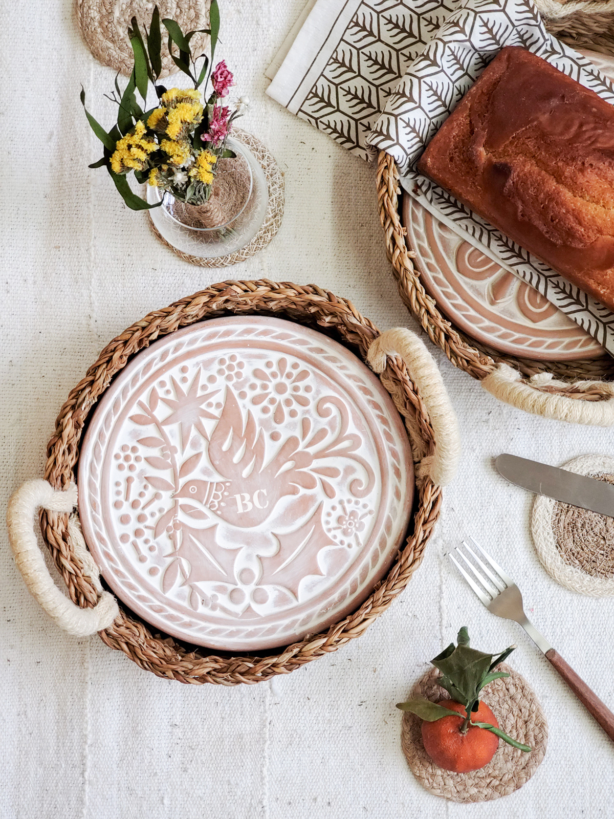 Monogrammed bread warmer and handwoven seagrass basket featuring a bird design, perfect for serving warm bread.